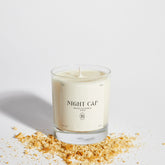 Boujie Night Cap jar candle in a minimalist glass jar, surrounded by golden biscuit crumbs, evoking the warm and comforting scent of biscuit, buttermilk, and rum.